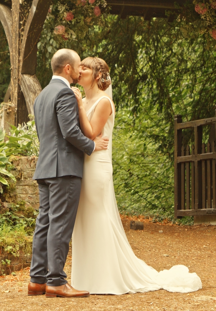Nicky and Rich kiss in front of the lytch gate.