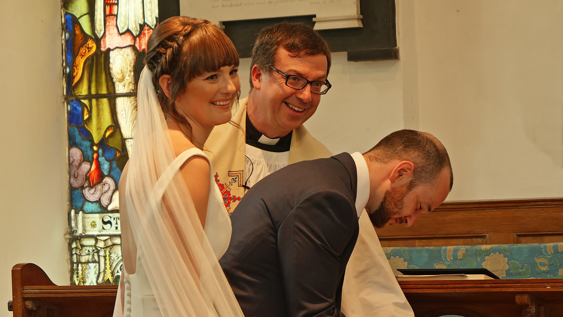 Rich signs the registry document whilst Nicky and Revd Tom watch on.