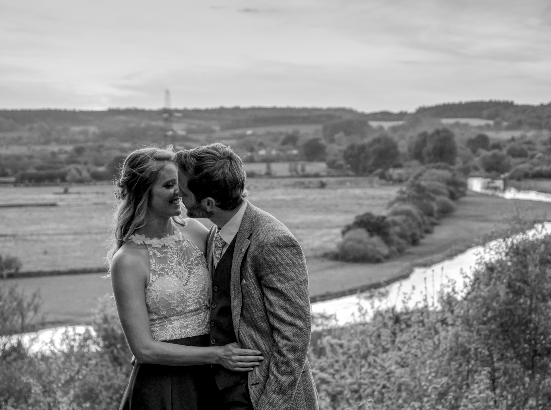 Sophie and Tom kiss, with a beautiful viewpoint behind them.
